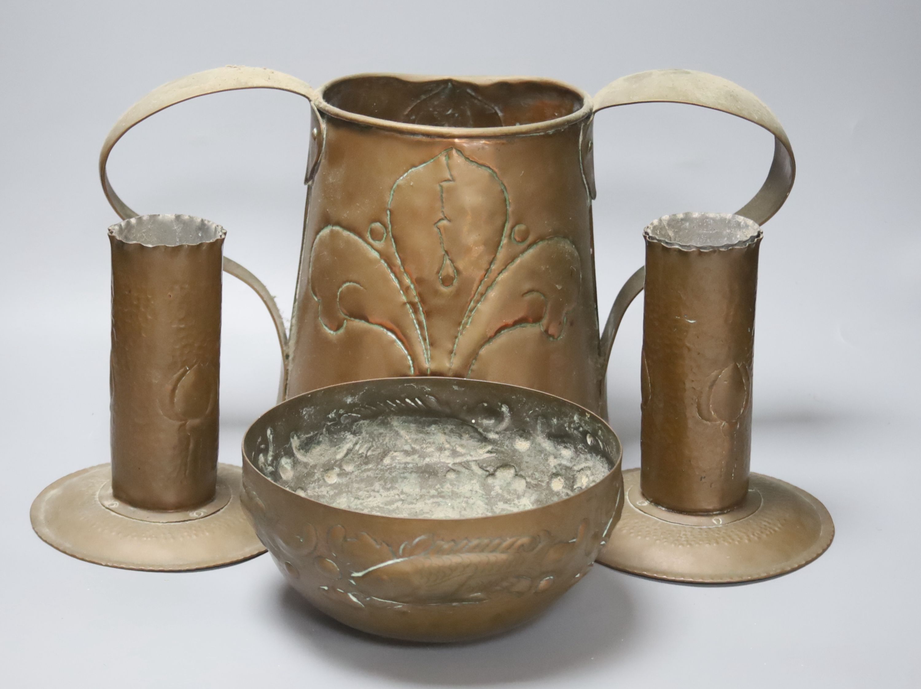 A Newlyn copper 'fish' bowl, together with a pair of Art Nouveau planished copper candlesticks and a similar two handled jug, largest 22cm